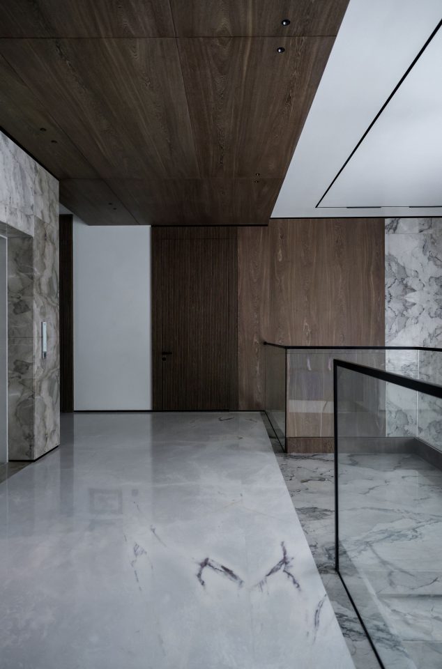 Atrio di un edificio con pavimento in marmo lucido, rivestimenti in legno e parapetto in vetro